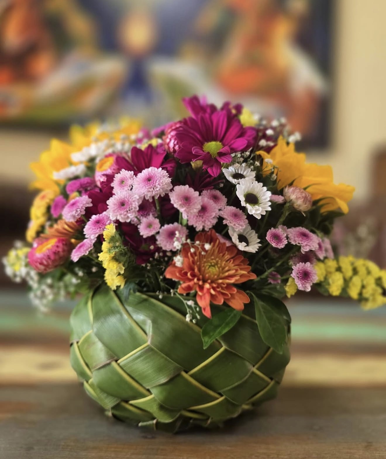 Woven leaf basket arrangement with pink chrysanthemums, gerberas, and sunflowers