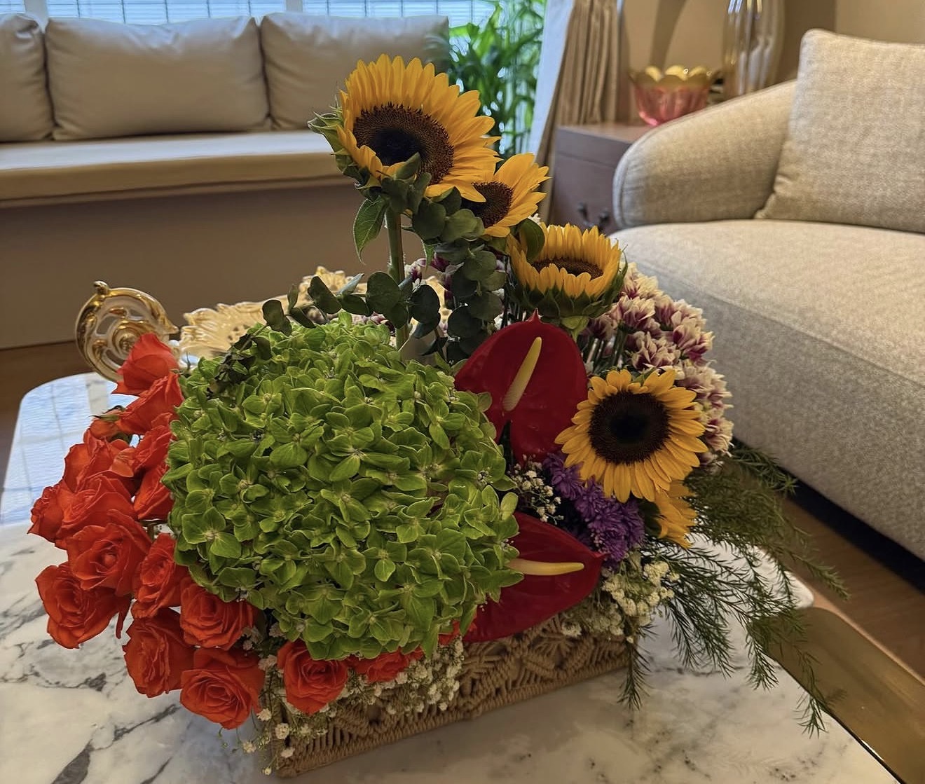 Sunflower and hydrangea arrangement with red roses in a woven basket