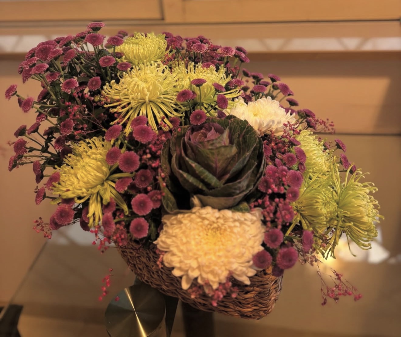 Autumn-toned arrangement with spider chrysanthemums, ornamental cabbage, and berries
